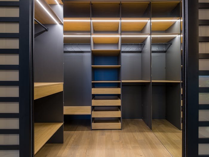 Walk-in wardrobe with open shelving, hanging space and soft lighting