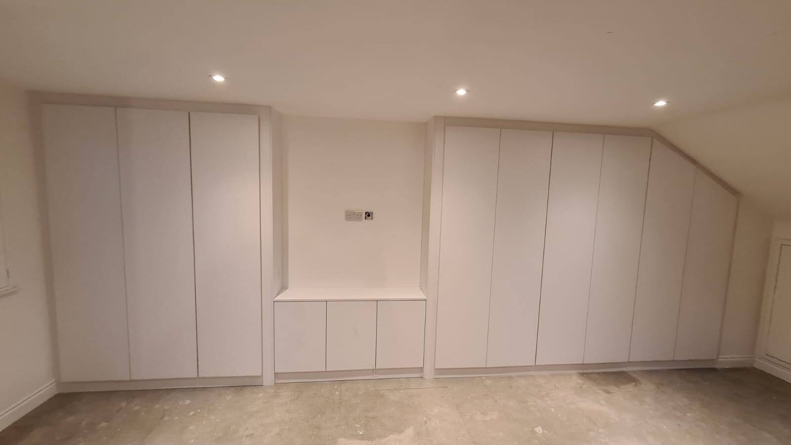 A project photo of wardrobes installed under a sloping ceiling in a loft conversion with low eaves