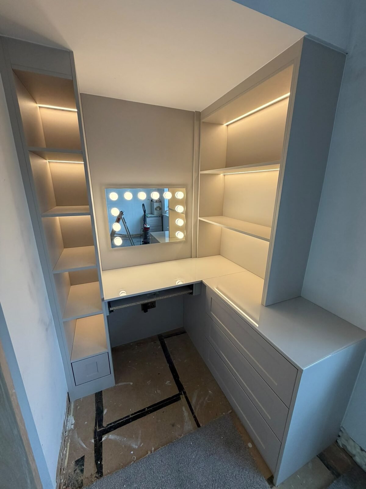 Built in dressing table in an alcove with drawers and LED-lit shelving
