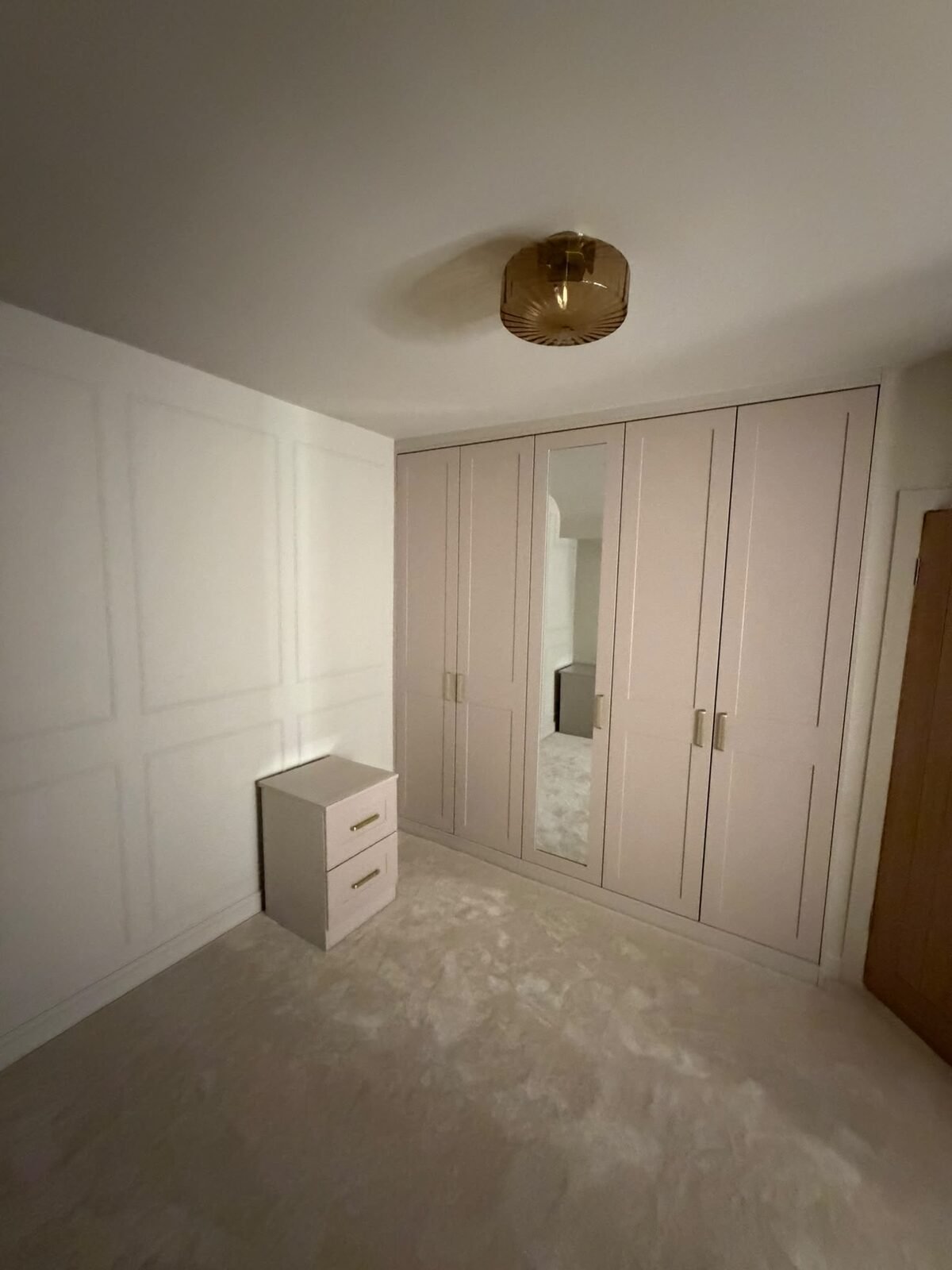 Built in shaker wardrobes with a full-length mirrored centre door and brass handles